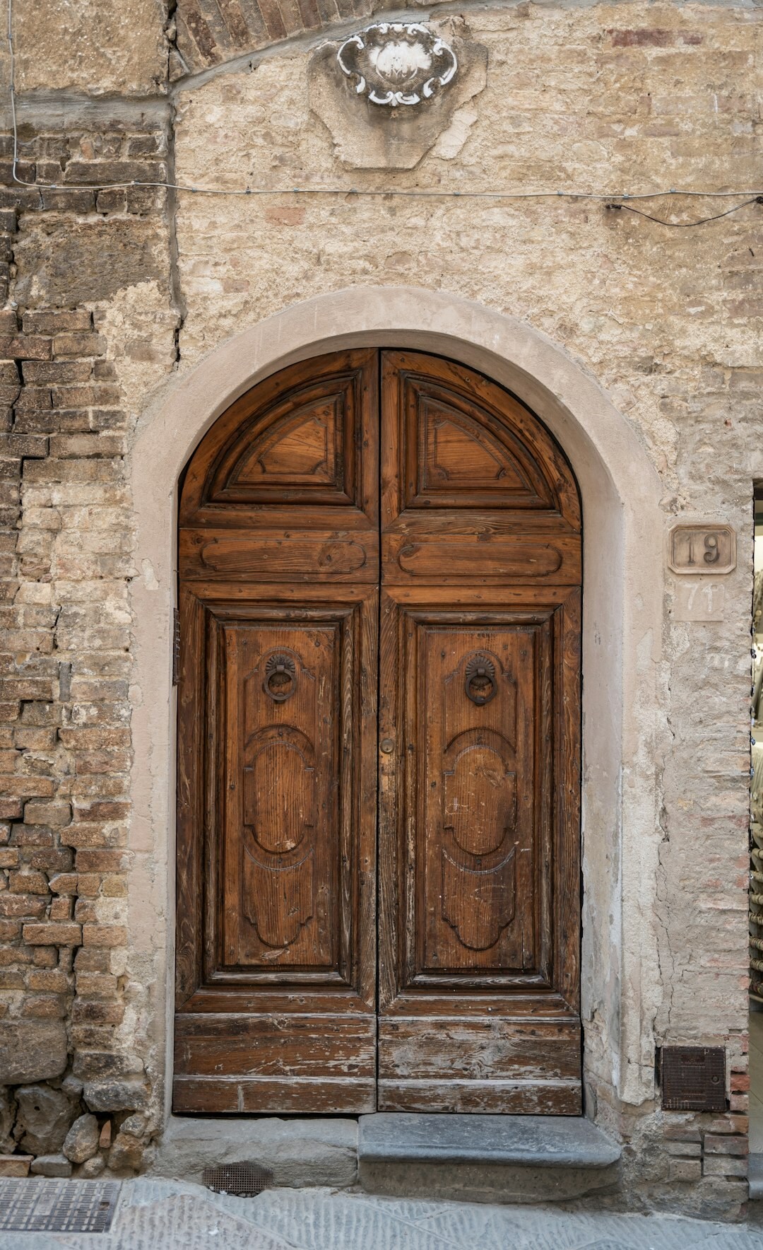 Weathered wooden door of an old stone house with brass handle